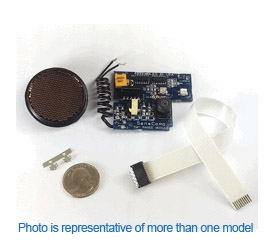 Components of an ultrasonic sensor kit shown with circuit board, mesh sensor head, ribbon cable, mounting clip, and a quarter for scale.