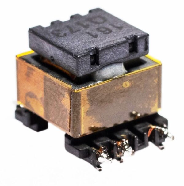 Rectangular electronic transformer with metallic copper-colored casing, black plastic top, and soldered surface-mount connections, shown angled on a white background.