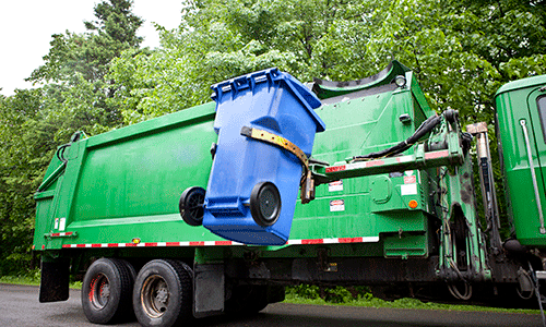 Garbage truck lifting a blue waste bin using hydraulic arms