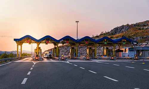 Multiple toll lanes at a highway checkpoint during sunset