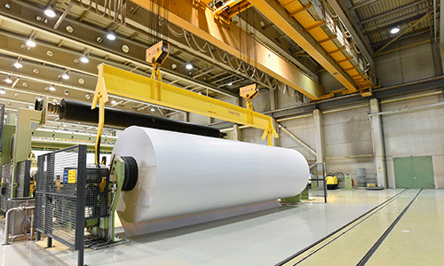 Large roll of white industrial material on a paper processing line