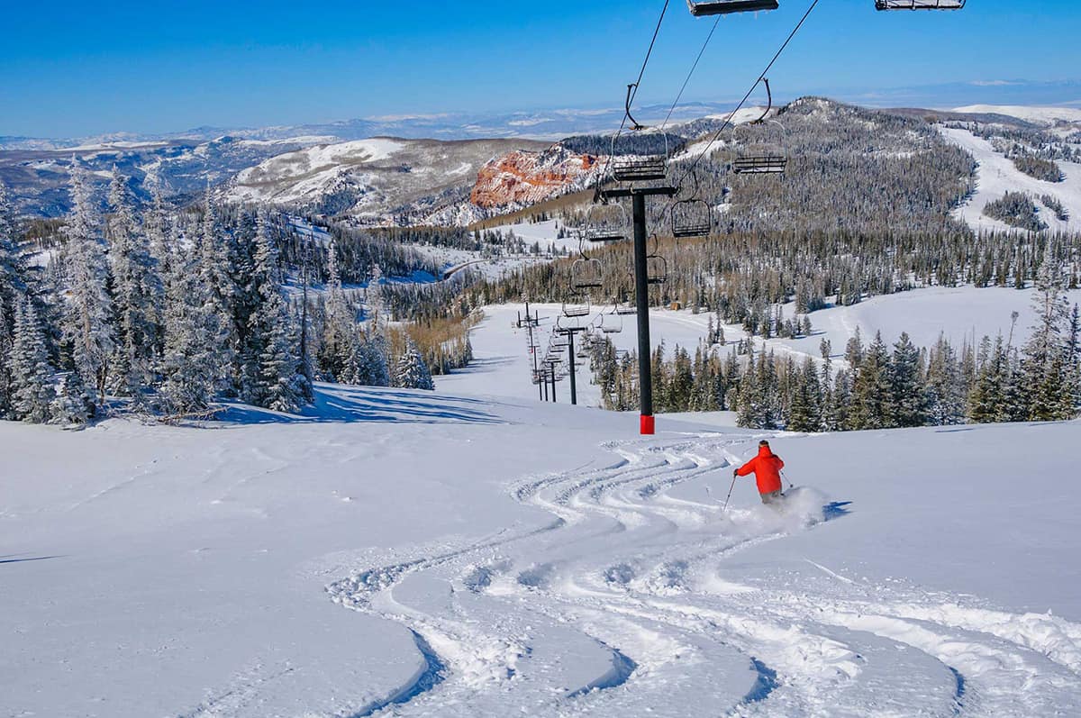 Ski run with tracked fresh powder below a chairlift, where electrostatic ultrasonic transducers track snow depth